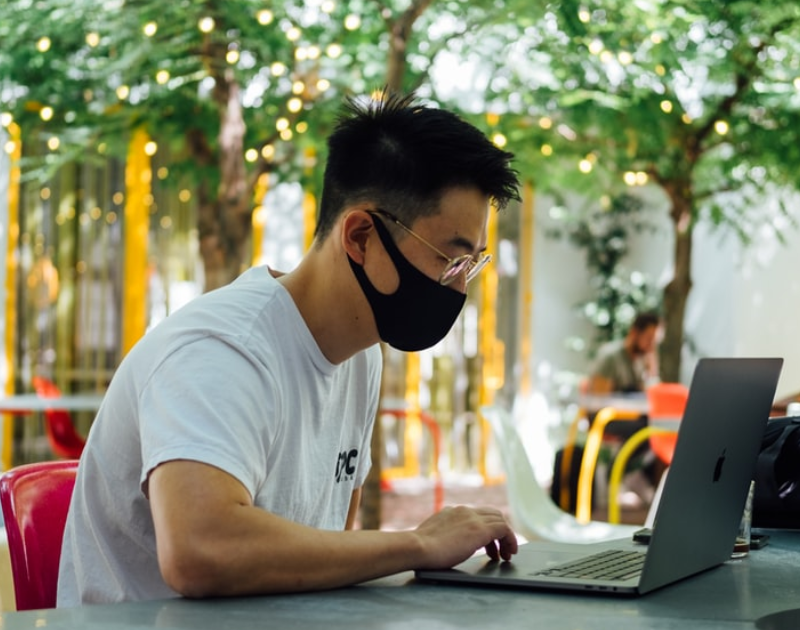 man using laptop while wearing mask